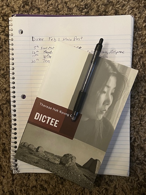 Picture of Theresa Hak Kyung Cha's book Dictee, with black pen, sitting atop notebook, on brown carpet. 