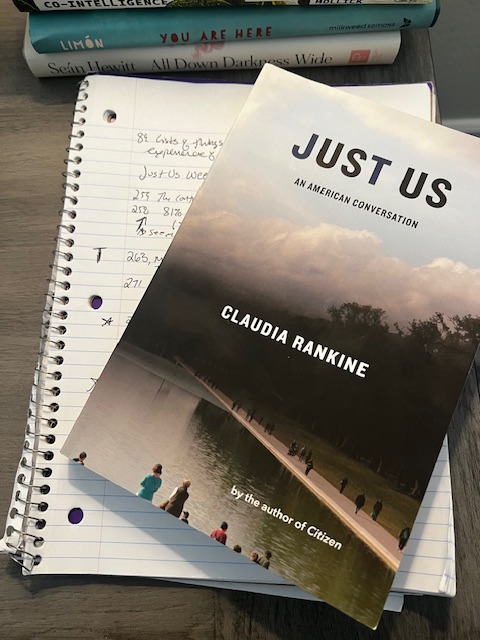 Claudia Rankine's book, Just Us, sitting atop open spiral notebook with notes in black ink.